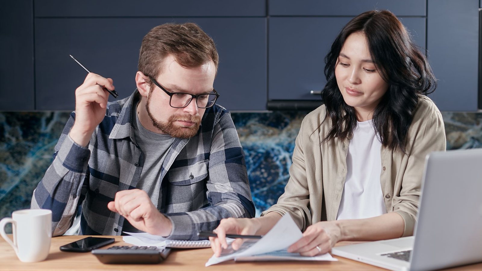 A couple is reviewing and calculating their household bills together at home.
