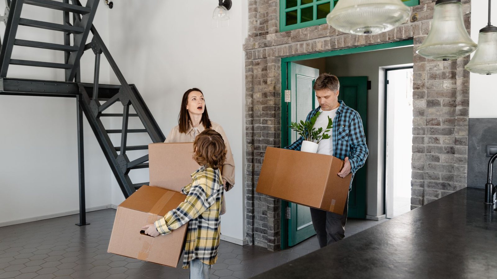 A family moving into their new home, carrying boxes and belongings indoors.